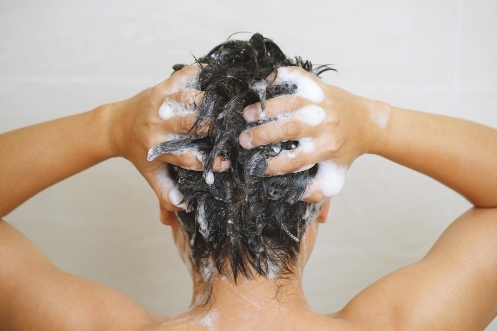 A man is washing his hair with shampoo