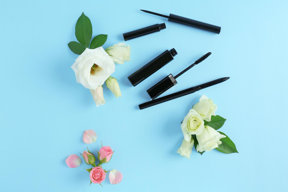 Mascara and flowers on blue background