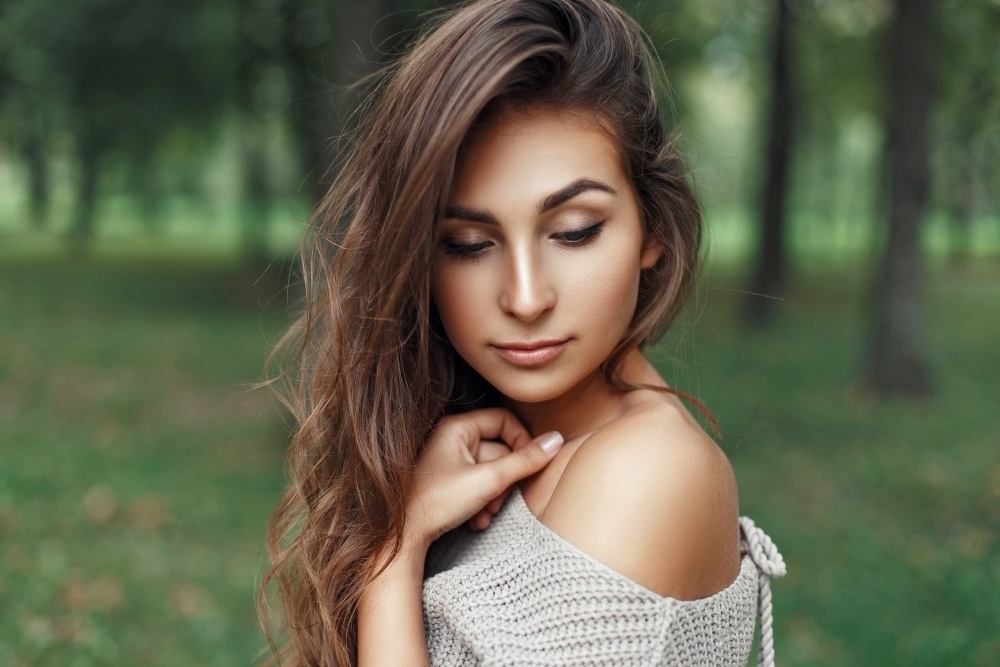 Pretty young girl with the hairstyle in vintage stylish sweater looks down
